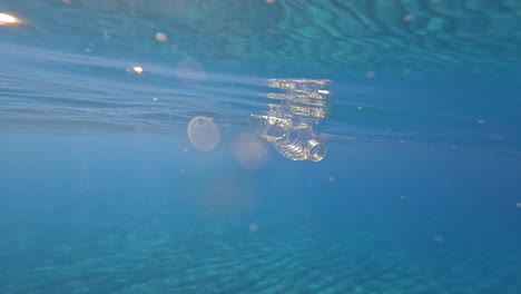 Botella-De-Plástico-En-Agua-Azul