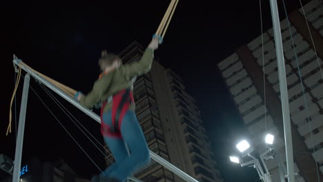 Niño-Divirtiéndose-En-Un-Trampolín-Bungee-En-El-Parque-De-Diversiones-Por-La-Noche