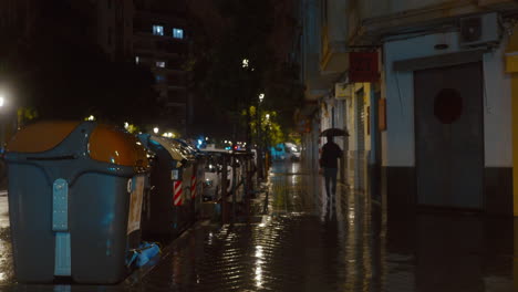 Hombre-Con-Paraguas-Caminando-Bajo-La-Llovizna-En-La-Ciudad-De-Noche