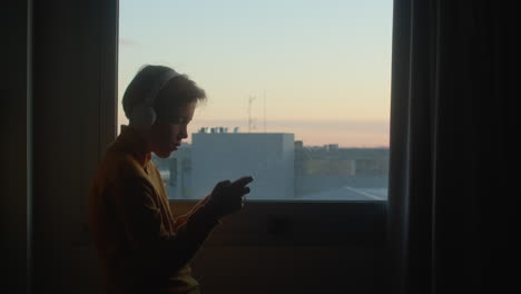 Teenager-playing-phone-at-sunrise