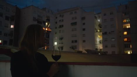 Eine-Junge-Frau-Mit-Einem-Glas-Wein-Auf-Einem-Balkon