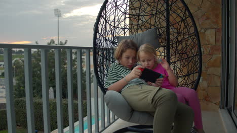 Siblings-playing-video-games-on-swing-chair