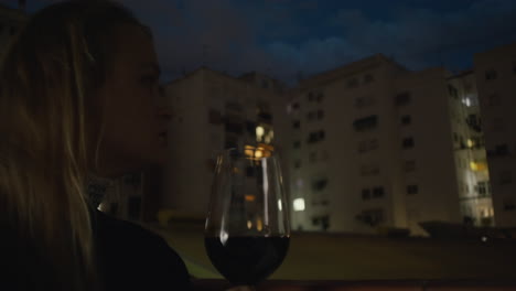 Eine-Junge-Frau-Hält-Ein-Glas-Wein-Auf-Einem-Balkon