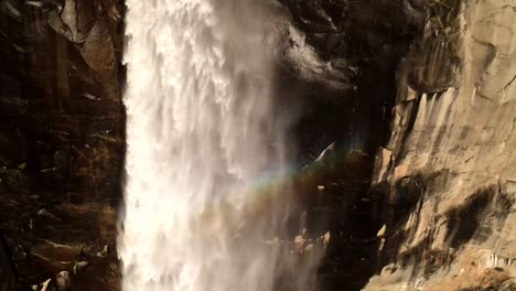 A-picturesque-beauty-of-Bridalveil-Falls-as-it-cascades-and-glides-down,-with-a-rainbow-taking-shape-within-the-falling-water