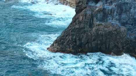 Ocean-wave-rolls-in-and-crashes-on-the-rock-cliffs-of-Los-Gigantes,-Tenerife