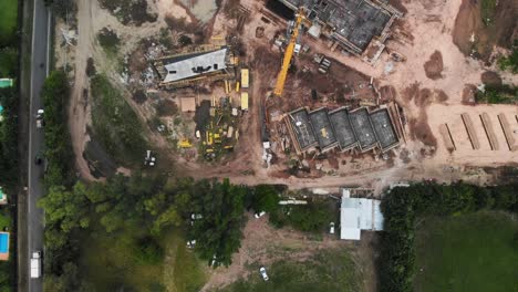 Aerial-view-of-a-construction-site-with-a-central-working-crane-amid-building-activities
