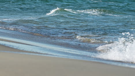 Sanfte-Wellen-Plätschern-Am-Strand,-Das-Klare-Wasser-Reflektiert-Das-Sonnenlicht-In-Einer-Ruhigen-Umgebung