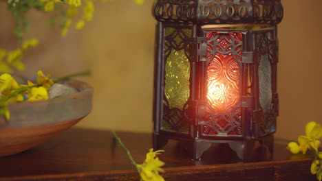 Panning-shot-of-soothing-candlelight-environment-with-rustic-candelabra,-yellow-flowers,-natural-stone-wall