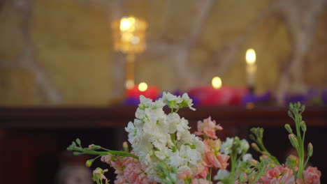 Dynamic-pan-shot-of-blooming-flowers-in-a-relaxing-candle-lit-environment-with-natural-stone-wall-and-a-pleasing-shallow-depth-of-field