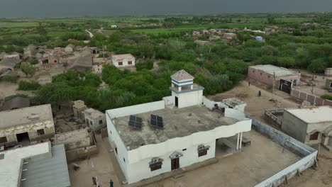 Aerial-drone-rotating-shot-over-village-houses-near-Mirpurkhas,-Sindh,-Pakistan-on-a-cloudy-evening