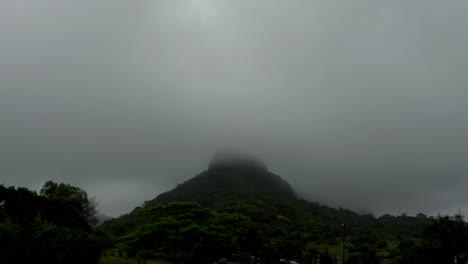 The-phone-camera-is-moving-from-the-bottom-to-the-top,-where-there-is-a-lot-of-fog-around-a-tall-mountain