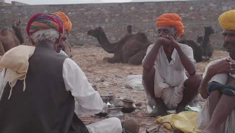 Männer-Und-Tiere-Entspannen-Sich,-Pushkar-Kamelmesse,-Zeitlupe,-Schwenk-Nach-Links