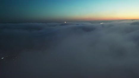 Ascending-drone-shot-through-dense-Clouds-during-sunset-over-lighting-city-of-Atlanta-City