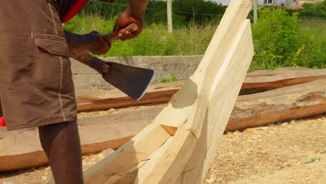 African-carpenters-carving-wooden-fishing-boats-with-adzes-in-shipyard