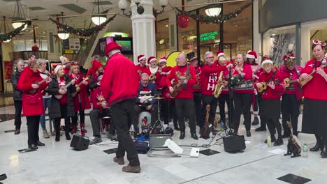 Un-Coro-Navideño-Con-Uniformes-Rojos-Entretiene-A-Los-Compradores-En-El-Centro-Comercial-St-Stephen&#39;s-Green.