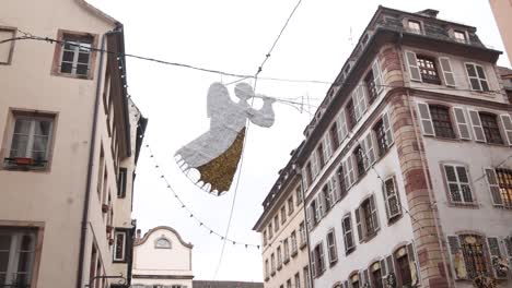 angel-decoration-floating-above-european-city-street-near-Festive-Christmas-market-in-Strasbourg,-France-Europe