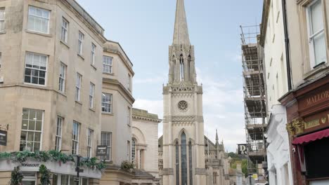 Several-people-walk-along-a-busy-corner-with-a-Church-in-the-background