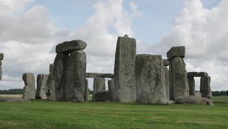 Stonehenge,-England,-under-a-blue-sky-with-white-clouds-and-some-beautiful-black-birds-flying-around-the-rocks