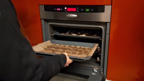 Putting-Christmas-gingerbread-cookies-in-the-oven-to-bake