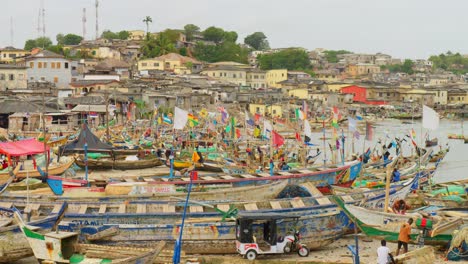 Fishing-boats-and-buildings-by-harbor-in-windy-Cape-Coast,-Ghana,-wide