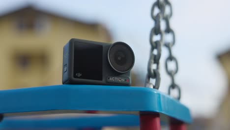 DJI-Osmo-Action-4-Kamera-Ruht-Auf-Schaukel-Im-Park-Mit-Bokeh-Hintergrund