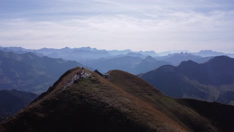 Drone-flying-straight-over-Molseon-summit-while-people-hiking-there,-background-is-filled-with-mountains