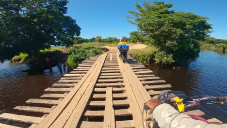 POV:-Transporte-A-Través-Del-Puente-De-Madera-Sobre-El-Lago-Con-Moto