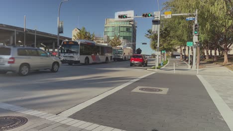 Houston-Metro-buses-turning-left-in-early-afternoon-as-the-camera-follows,-panning-right-in-downtown-Houston,-Texas