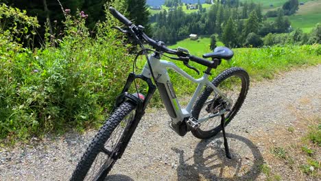 Sporty-electric-mountain-bicycle-on-a-beautiful-sunny-hill-with-green-forest-and-mountain-view,-fun-summer-adventure-day-sport-activity-in-Serfaus-Fiss-Ladis-bikepark,-biking-in-Tyrol-Austria,-4K-shot
