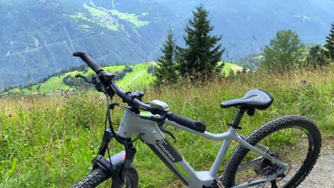 Sporty-electric-mountain-bicycle-on-a-beautiful-sunny-hill-with-green-forest-and-mountain-view,-fun-summer-adventure-sport-day-activity-in-Serfaus-Fiss-Ladis-bikepark,-biking-in-Tyrol-Austria,-4K-shot