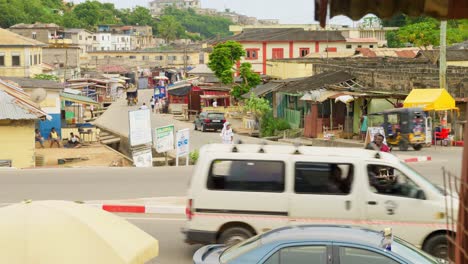 Coches-Y-Motos-En-La-Carretera-Por-Casas-Primitivas-En-Cape-Coast,-Ghana