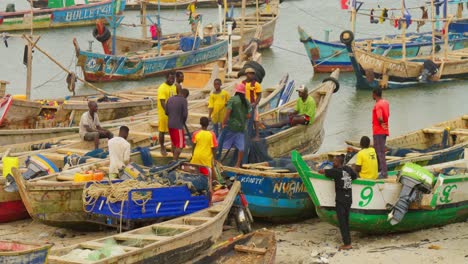 Fishermen-sort-out-nets-on-colorful-fishing-boats-at-Cape-Coast,-Ghana