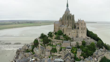 Luftdrohnenaufnahme-Im-Schloss-Mont-Saint-Michel,-Es-Gibt-Große-Gärten-Und-Touristen,-Die-Fotografieren