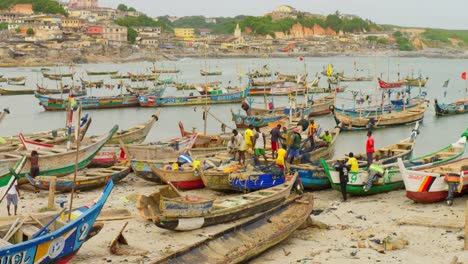 Fishermen-sort-out-nets-on-boats-in-harbor-at-Cape-Coast,-Ghana,-wide