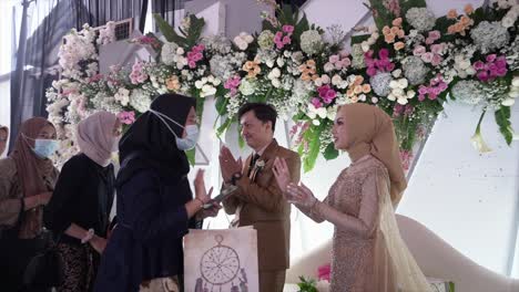 Bride-and-groom-welcomed-invited-guests-by-shaking-hands-in-front-of-the-wedding-reception-altar