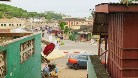 Buildings,-street-traffic-and-green-hill-at-Cape-Coast-in-Ghana,-wide