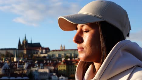 Girl-peacefully-stand-and-open-eyes-enjoying-Prague-city-during-golden-hour