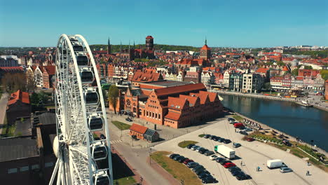 Aerial-shot-of-Ferris-Wheel-in-Gdańsk,-Poland-with-old-town-in-the-background-at-sunny-summer-day