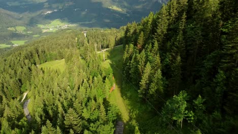 Long-rope-way-leading-down-a-mountain-surrounded-by-green-fields-and-forests-in-the-Alps-in-Lofer,-Austria