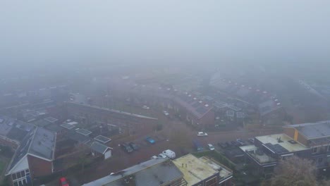 Aerial-of-a-beautiful-suburban-neighborhood-covered-in-thick-mist-on-a-cold-winter-day---drone-flying-backwards