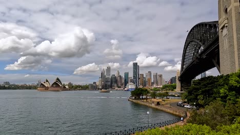 Vista-Panorámica-Del-Puente-Del-Puerto-De-Sydney-A-La-Izquierda-Con-La-ópera-Y-El-Horizonte-De-La-Ciudad-Al-Fondo