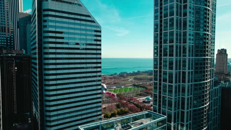 Epische-Luftaufnahme-Des-Jay-Pritzker-Pavilion-Amphitheaters-Und-Der-Bohne-Zwischen-Zwei-Wolkenkratzern-In-Der-Innenstadt-Von-Chicago,-USA