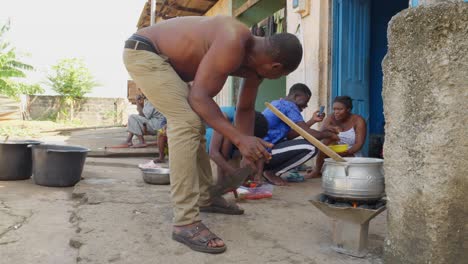 El-Hombre-Agita-El-Fuego-De-La-Olla-Donde-Se-Cocina-Banku,-Mezcla-De-Maíz-Y-Mandioca,-Cocina-De-Ghana.