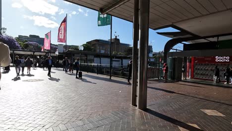 Menschen,-Die-An-Einem-Sonnigen-Tag-Durch-Den-Circular-Quay-In-Sydney-Laufen,-Während-Fahnen-Im-Wind-Wehen