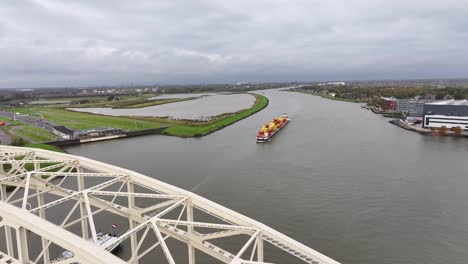 Wide-angle-aerial-dolly-footage-of-steel-bridge-and-loaded-cargo-ship