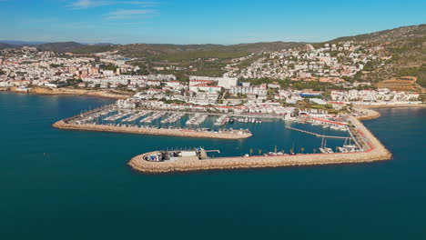 Drone-captures-docking-town-in-sunny-weather-with-a-beautiful-blue-sea-coast-backdrop