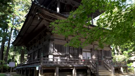 Vista-De-Esquina-De-La-Pagoda-Oeste-Kongobu-ji-Saito-En-Koyasan-En-Un-Entorno-De-Bosque-Sereno-Con-Una-Rama-De-árbol-Verde-En-Primer-Plano