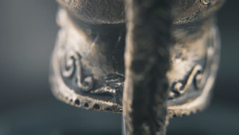 A-close-up-macro-detailed-shot-from-behind-of-a-spartan-face-design,-warrior-ancient-greek-bronze-helmet,-on-a-360-rotating-stand,-studio-lighting,-4K-smooth-movement