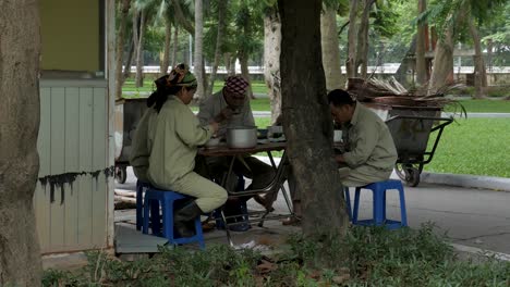 Equipo-De-Mantenimiento-Del-Parque-Nacional-De-La-Ciudad-De-Hanoi-Sentado-Almorzando-Juntos