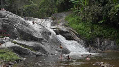 Shot-of-local-kids-water-sliding-on-rocks-bathing-in-Mo-Pang-Waterfall-in-Mae-Na-Toeng,-Pai-District,-Mae-Hong-Son,-Thailand